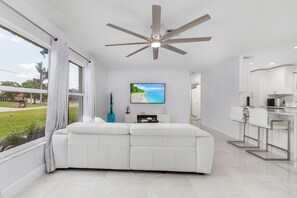 Enjoy a beach view from the large window, with a ceiling fan above and a flat-screen TV on the wall.