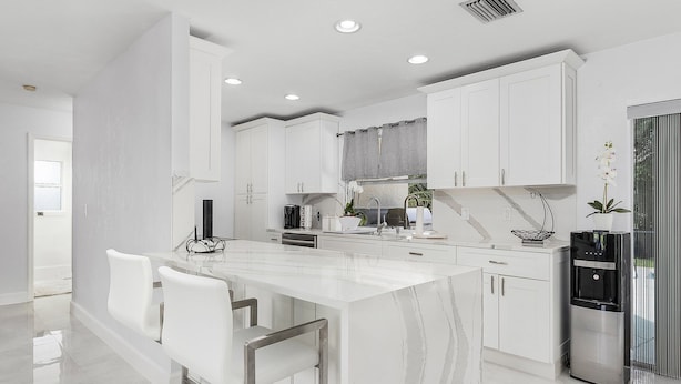 A modern kitchen with white cabinetry, a marble countertop, and stainless steel appliances. - Fairview Getaway (Fort Myers)