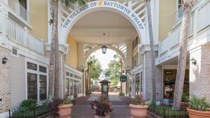 Een inkom naar The Village of Baytowne Wharf met een overdekte doorgang, gebouwen van baksteen en potplanten.