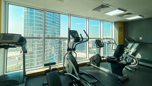 Ein Fitnessraum mit Cardiogeräten, großen Fenstern und motivierenden Wandbildern.