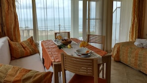 A room with a dining table set for two, a sofa, and a bed. - July Morning Seaside Resort (Kavarna)