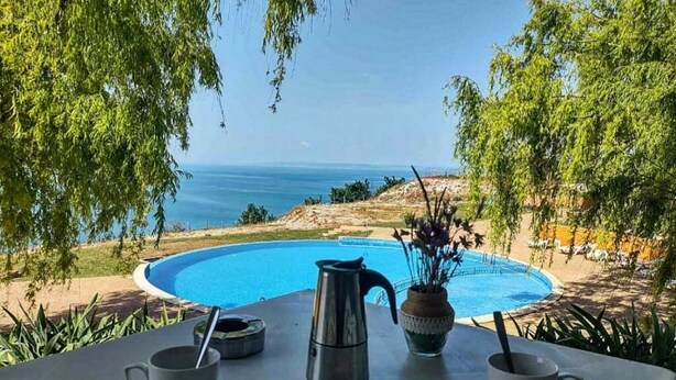 A poolside view with a clear view of the sea, a table with a kettle and a vase of flowers, and a chair. - July Morning Seaside Resort (Kavarna)