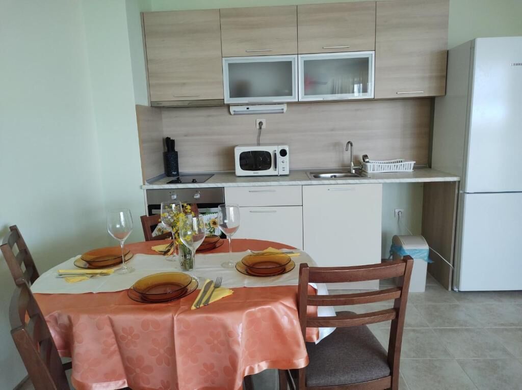 Une cuisine de taille réduite, dotée de meubles de rangement en bois, d’un four à micro-ondes, d’un évier et d’un réfrigérateur.