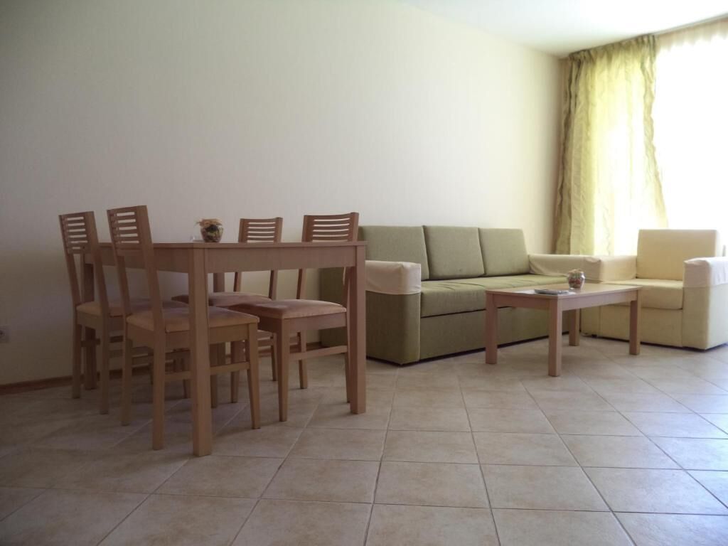 A living room with a dining table, four chairs, a sofa, a coffee table, and a window with curtains.
