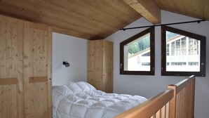 A bedroom with a wooden ceiling, a bed, and two windows with black frames. - 250m from resort center, 1st floor, balcony, parking, tv, ski locker, 60m², Pralognan-la-Vanoise (Pralognan-la-Vanoise)