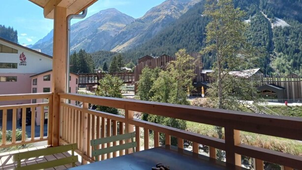 A balcony with a view of mountains and buildings. - 250m from resort center, 1st floor, balcony, parking, tv, ski locker, 60m², Pralognan-la-Vanoise (Pralognan-la-Vanoise)