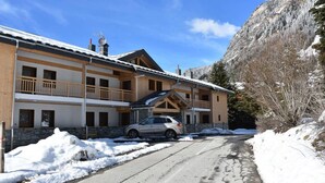 A two-story lodge with a ski lift, a car parked in front, and snow-covered surroundings. - 250m from resort center, 1st floor, balcony, parking, tv, ski locker, 60m², Pralognan-la-Vanoise (Pralognan-la-Vanoise)