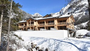 A multi-story chalet with balconies, surrounded by snow-covered mountains and trees. - 250m from resort center, 1st floor, balcony, fireplace or stove, parking, tv, ski locker, 67m² (Pralognan-la-Vanoise)