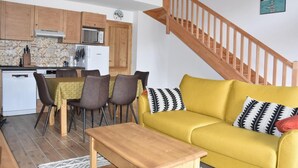 A compact living space with a dining area, a yellow sofa, and a wooden staircase. - 250m from resort center, 1st floor, balcony, fireplace or stove, parking, tv, ski locker, 67m² (Pralognan-la-Vanoise)