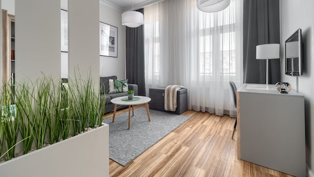 A modern living room with a grey sofa, a round coffee table, and a grey cabinet. - MARGI Maya Apartments (Szczecin)