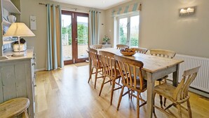 Un comedor con una mesa y sillas de madera, un bol de fruta y una lámpara sobre una encimera.