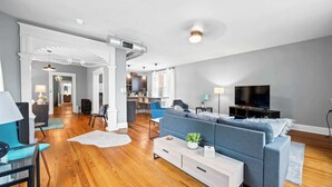 A modern living room with a grey sofa, a TV, and a wooden floor. - 8 min to Stadiums & Dwntn Cincy, 1BR in Ludlow KY (Ludlow)