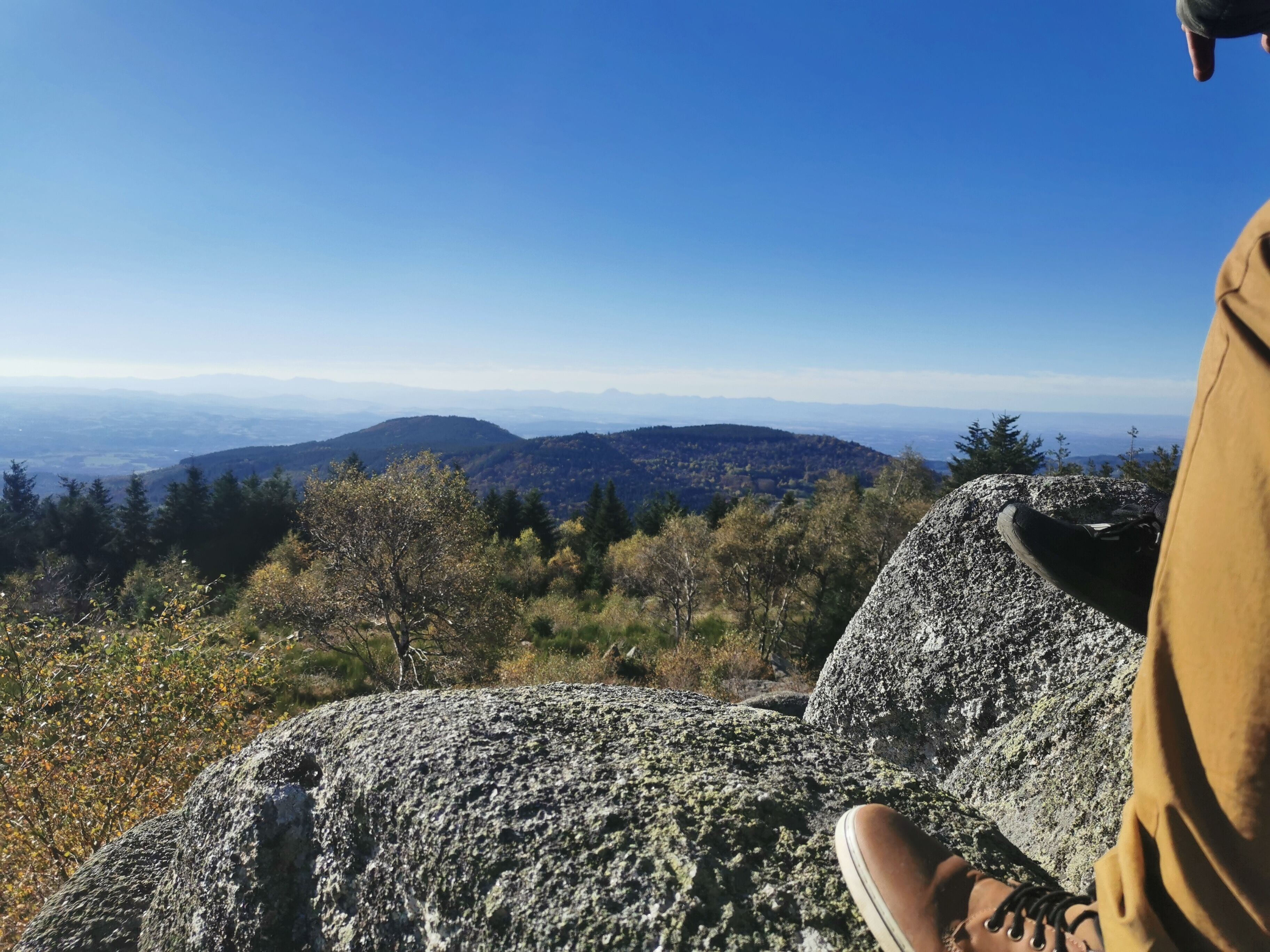 Une formation rocheuse offrant une vue sur des montagnes lointaines et des collines boisées.