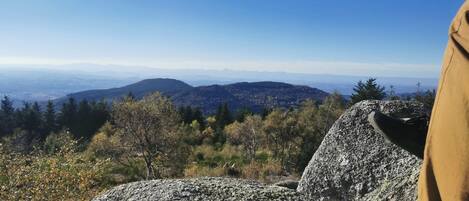 A rocky outcrop with a view of distant mountains and forested hills.