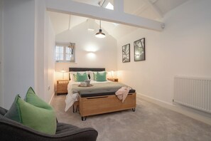 Ein Schlafzimmer mit Bett, Nachttischen, Heizkörper und einem Fenster mit Jalousien.