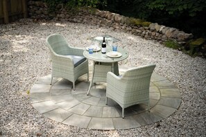 An outdoor patio with a round table, two wicker chairs, and a bottle of wine. - Contemporary Home Nr Kirkby Lonsdale - Spacious Garden (Carnforth)
