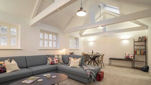 A modern living room with a grey sectional sofa, a coffee table, and a dining area with a table and chairs. - Contemporary Home Nr Kirkby Lonsdale - Spacious Garden (Carnforth)