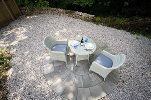 A circular outdoor seating area with a stone table and wicker chairs. - Contemporary Home Nr Kirkby Lonsdale - Spacious Garden (Carnforth)