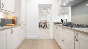 A modern kitchen with white cabinets, a central island, and a dining area in the background. - Contemporary Home Nr Kirkby Lonsdale - Spacious Garden (Carnforth)