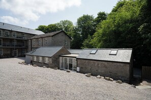 A stone building with a gravel courtyard, a second-story balcony, and a small attached structure with a sloped roof. - Contemporary Home Nr Kirkby Lonsdale - Spacious Garden (Carnforth)