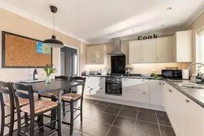 A modern kitchen with a central island, a dining area with chairs, and a kitchen island with a microwave.