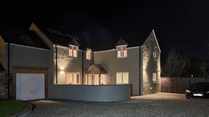 Ein zweistöckiges Haus mit einer Stein-Fassade, zahlreichen Fenstern und einer Auffahrt mit Kies.