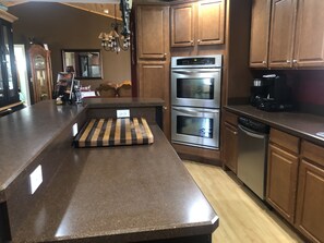A kitchen with a granite countertop, double ovens, a dishwasher, wooden cabinets, and a chandelier. - Horse show, casinos, lakes, trails, sand dunes, and numerous beaches nearby. (Kalkaska)