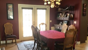 Un espace repas doté d’un plafond en bois, d’un lustre, d’une table à manger recouverte d’une nappe rouge et d’un tapis à motifs.