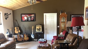 Un salon doté d’un ventilateur de plafond, d’une grande horloge et d’un téléviseur fixé au mur.