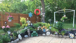 Un jardin agrémenté de diverses plantes en pot, d’une clôture en bois et d’une balançoire.