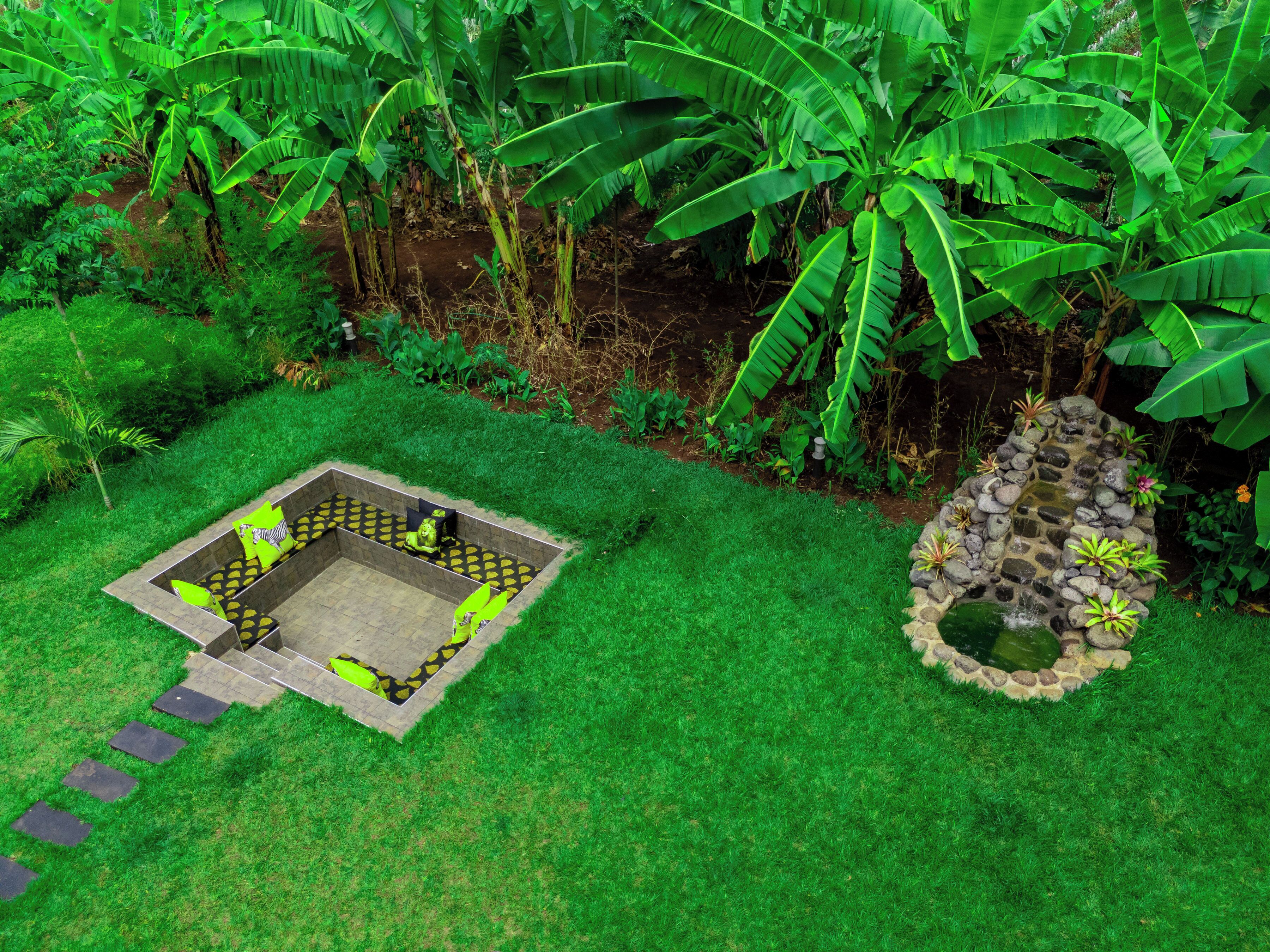 A garden with a stone pathway leading to a seating area with cushions.