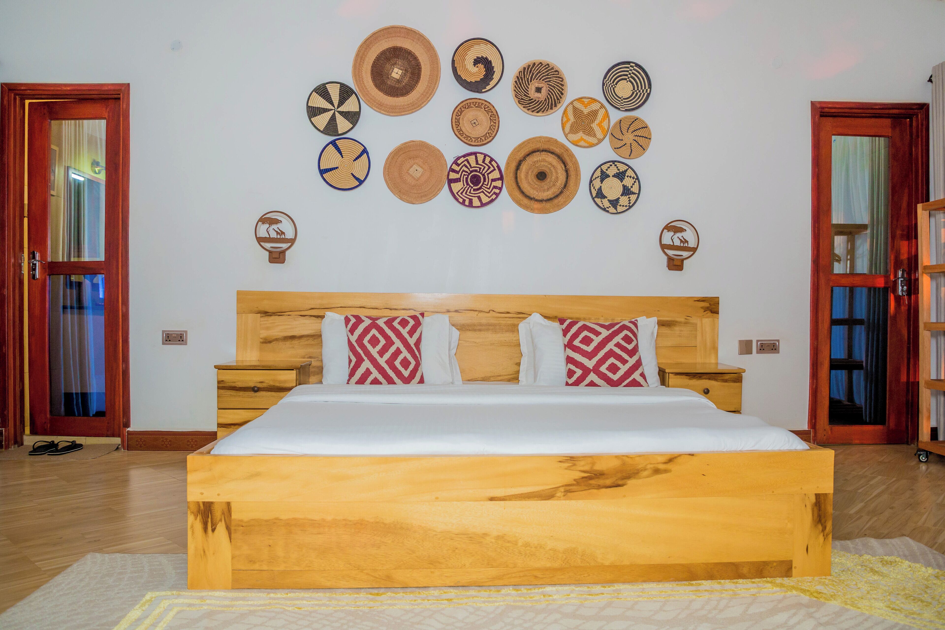 Ein Schlafzimmer mit einem hölzernen Bett, einer Wand voller gewebter Körbe und zwei Türen.