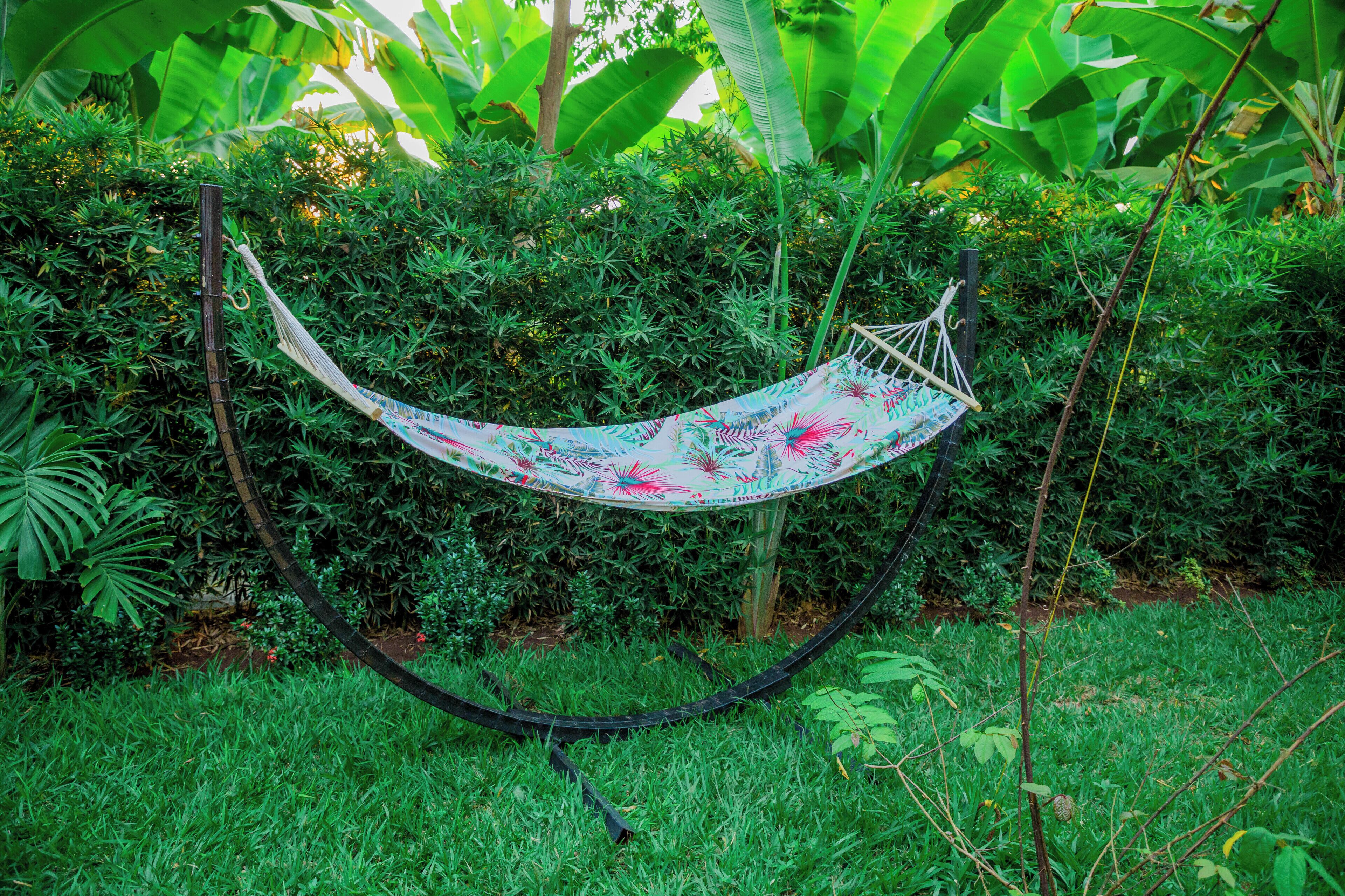 A hammock in a lush garden with dense foliage and banana plants in the background.
