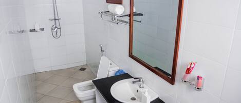 Un baño moderno con ducha, inodoro, lavamanos y espejo.