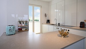 A modern kitchen with white cabinets, a countertop, a toaster, a coffee maker, and a decorative bowl.