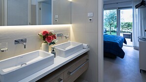 A modern bathroom with two sinks, a mirror, and a vase with flowers.