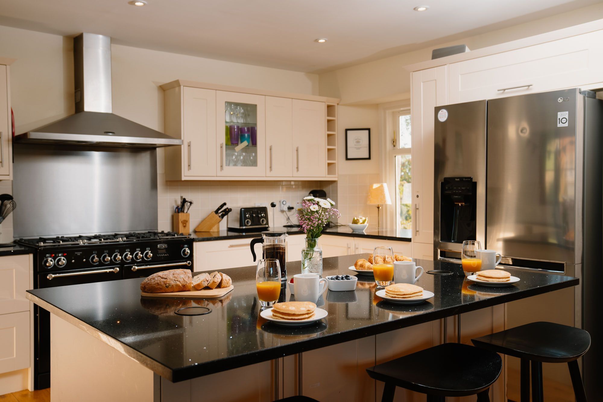 A modern kitchen with a central island, stainless steel appliances, and a breakfast setup.