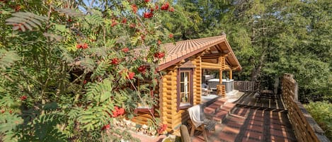 Una cabaña de madera con terraza de tejas, rodeada de árboles y bayas rojas.