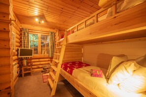 A cabin with a bunk bed, a television, and a window with curtains. - Beaver Creek Lodge -  a lodge that sleeps 8 guests  in 3 bedrooms (Aviemore)