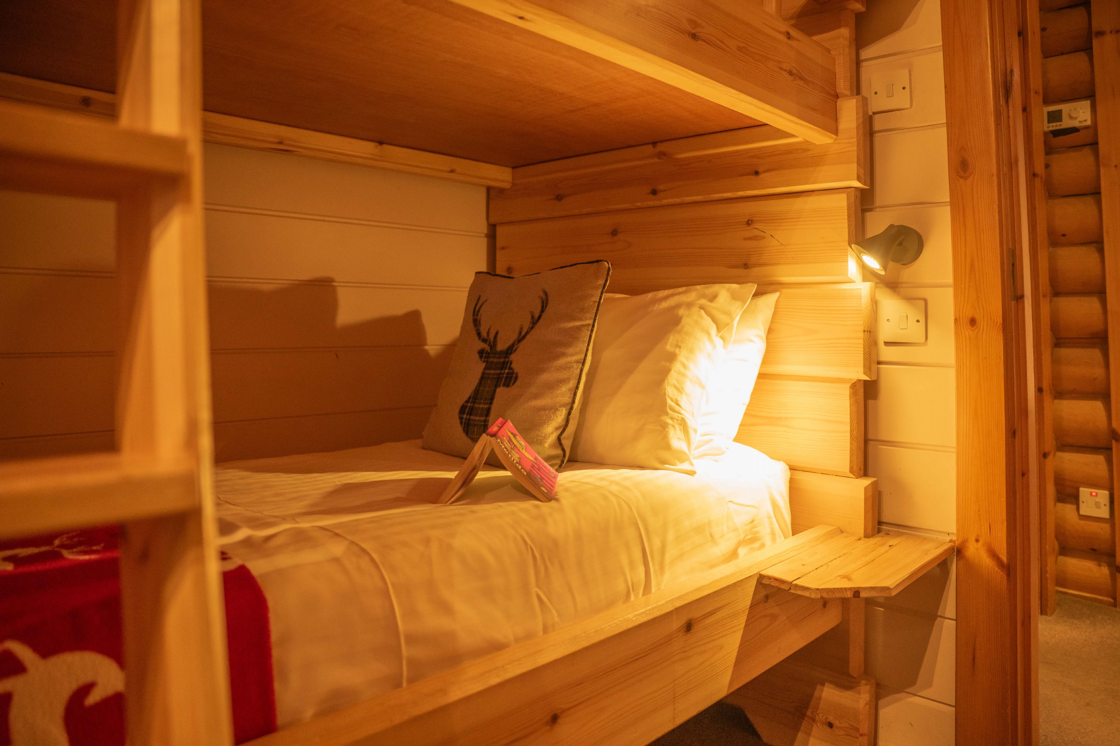 Un lit superposé en bois, avec une tête de lit, des oreillers et une table de chevet.