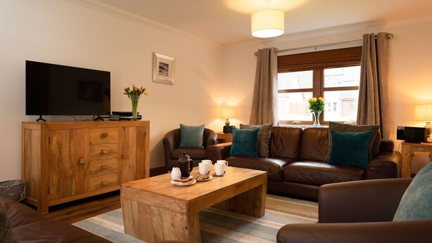 A living room with a wooden cabinet, a television, a sofa, and a coffee table.