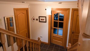 A wooden staircase leading to a room with a glass door, a framed picture on the wall, and a light fixture above the door.