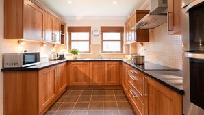 A modern kitchen with wooden cabinets, a black countertop, a microwave, a toaster, and a sink.