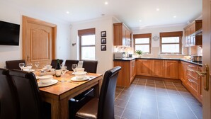 A modern kitchen with wooden cabinets, a dining table set for four, and a large window providing natural light.