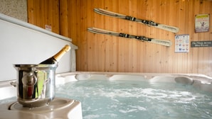 Un jacuzzi con esquíes colgados en la pared, una botella de champán y un letrero advirtiendo nadar bajo su propia responsabilidad.