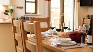 Una mesa de comedor dispuesta con platos, vasos y una olla roja, presumiblemente para servir comida.