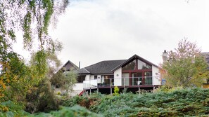 A modern house with a large glass window, surrounded by lush greenery. - sleeps 6 in 1 double bedroom, 1 twin (or superking), 1 full size bunk bed. (Aviemore)