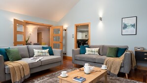 Ein modernes Wohnzimmer mit zwei grauen Sofas, einem Couchtisch und einem Bücherregal.