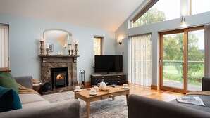 Ein Wohnzimmer mit Kamin, Fernseher und Blick ins Freie.