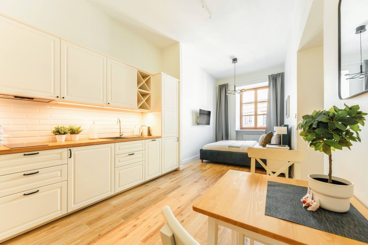 A modern kitchen with white cabinets, a wooden countertop, and a dining area with a table and chairs.